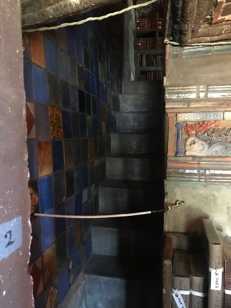 Narrow tiled staircase inside Fonthill Castle with rope barrier and built-in bookshelves