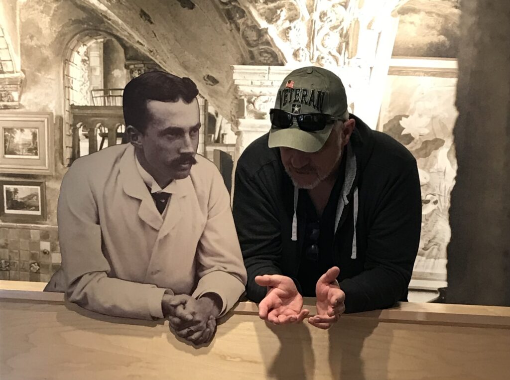 Visitor interacting with historic black-and-white figure display at museum exhibit