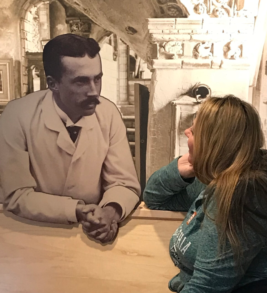 Visitor interacting with historic black-and-white figure display at museum exhibit