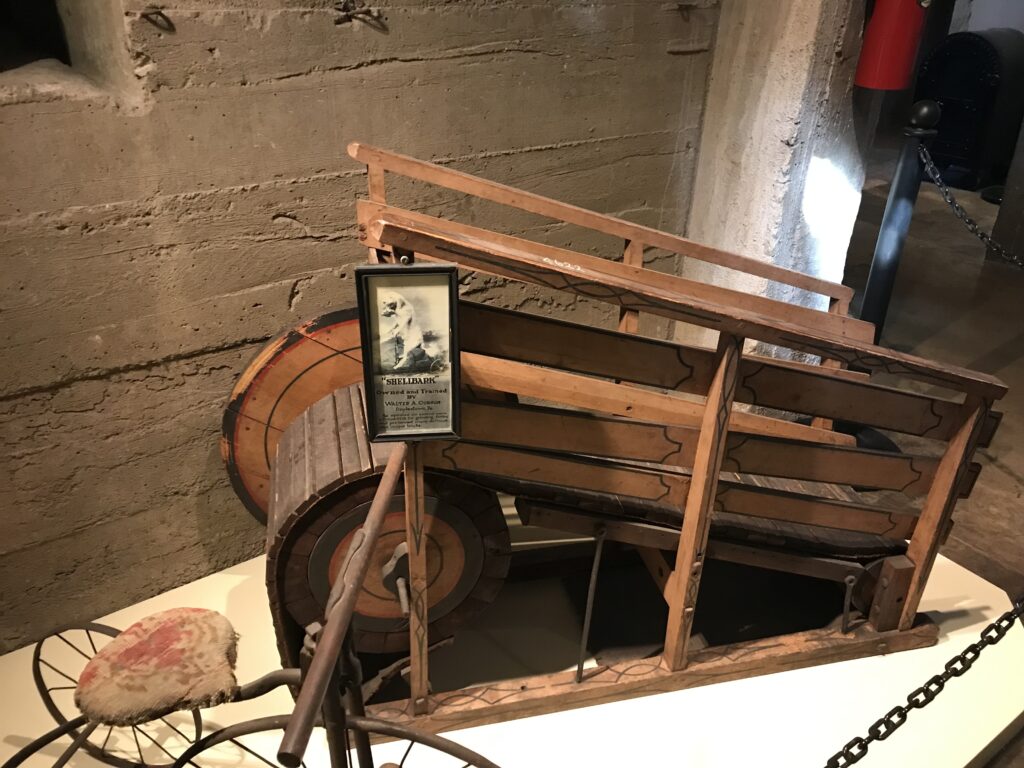 Antique wooden cart with large wheel displayed inside the Mercer Museum in Doylestown, Pennsylvania