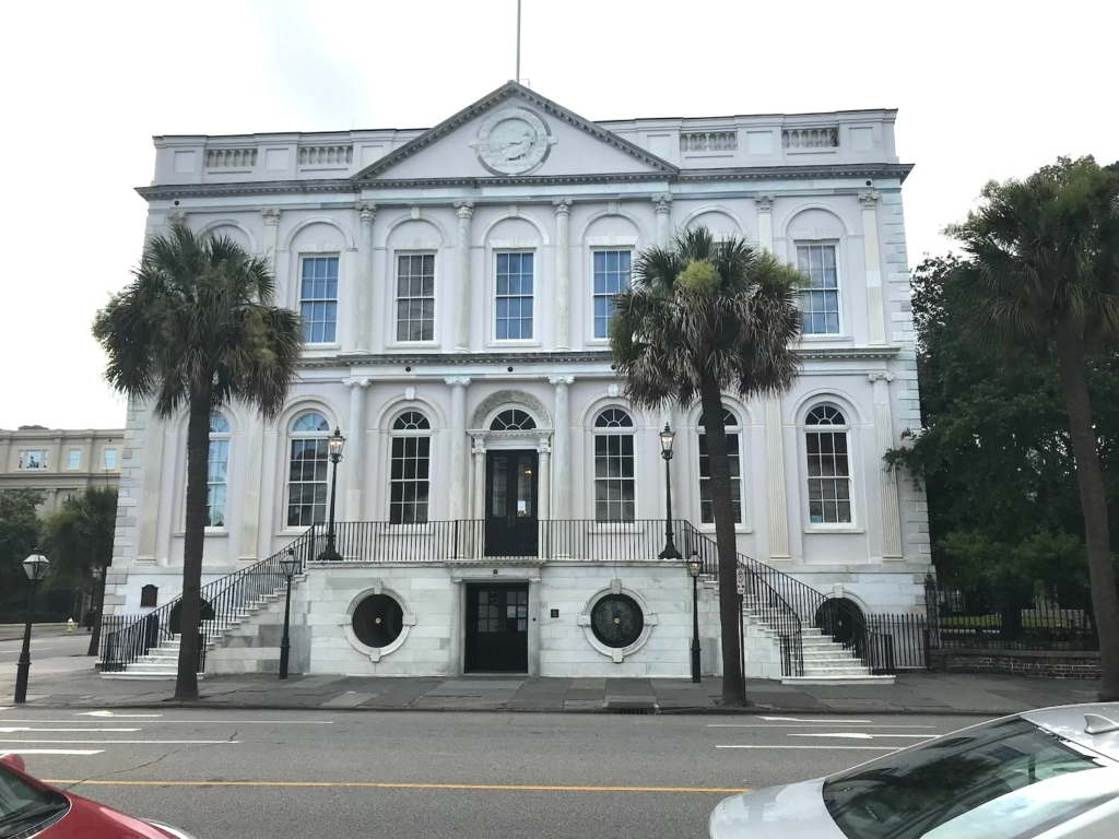 Historic Dock Street Theatre building with grand white facade and palm trees in downtown Charleston