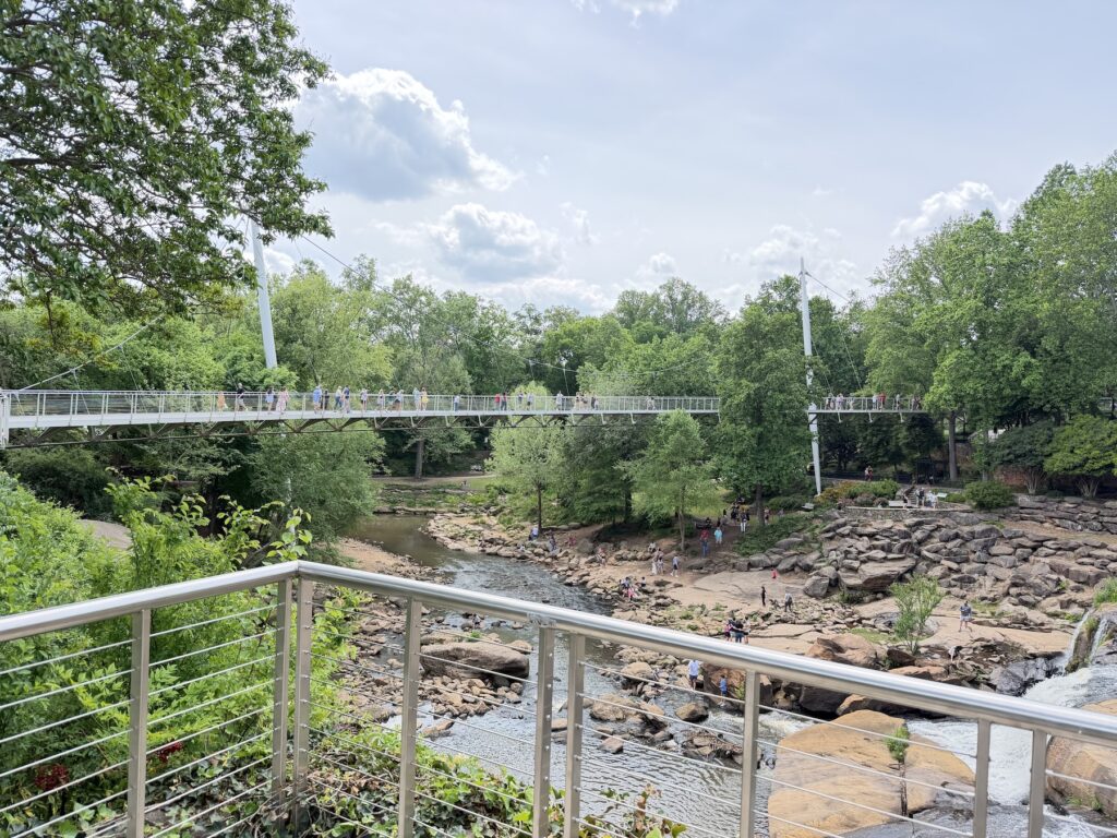 Liberty Bridge spanning the Reedy River in Falls Park, Greenville South Carolina with visitors walking across