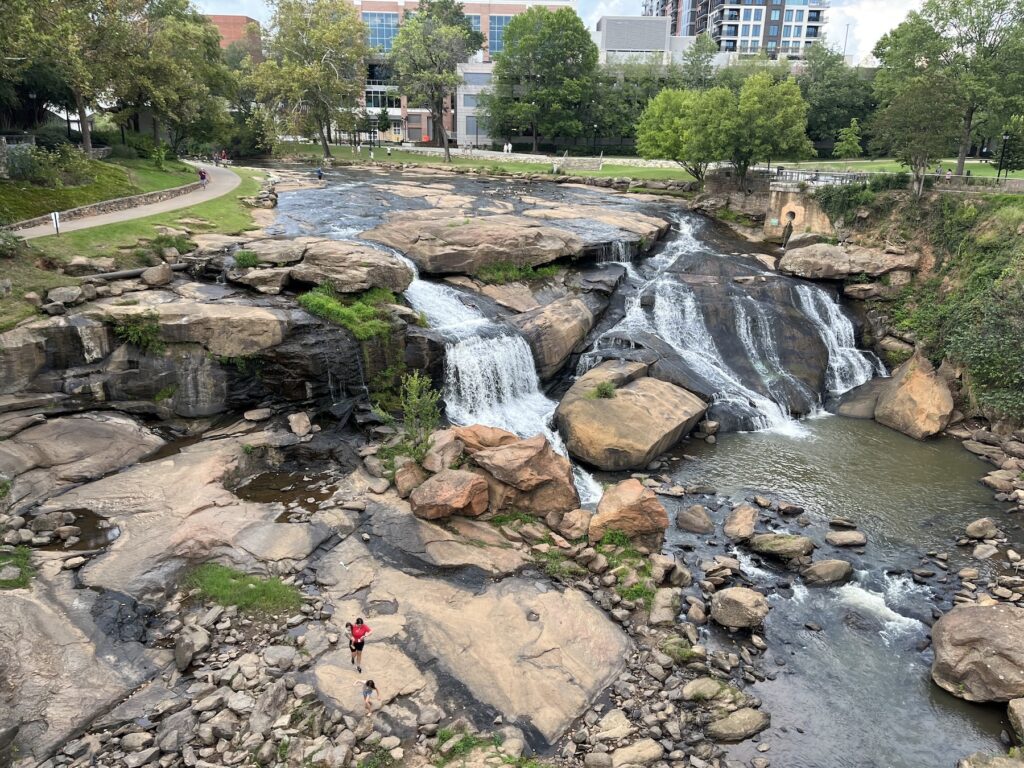 Wide view of Reedy River Falls and rocky riverbed in Falls Park, Greenville South Carolina