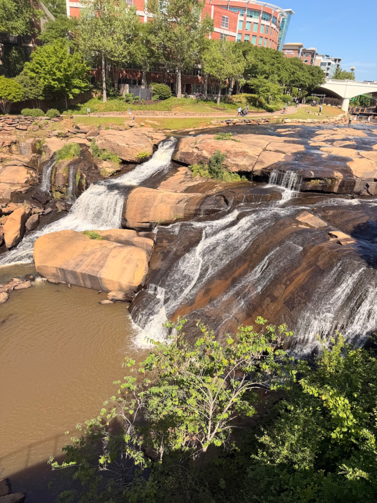 Reedy River Falls cascading over large rocks in downtown Greenville South Carolina with walking path above