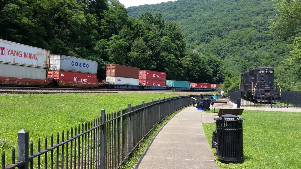 Freight train with shipping containers passing Horseshoe Curve in Altoona, Pennsylvania with historic locomotive on display