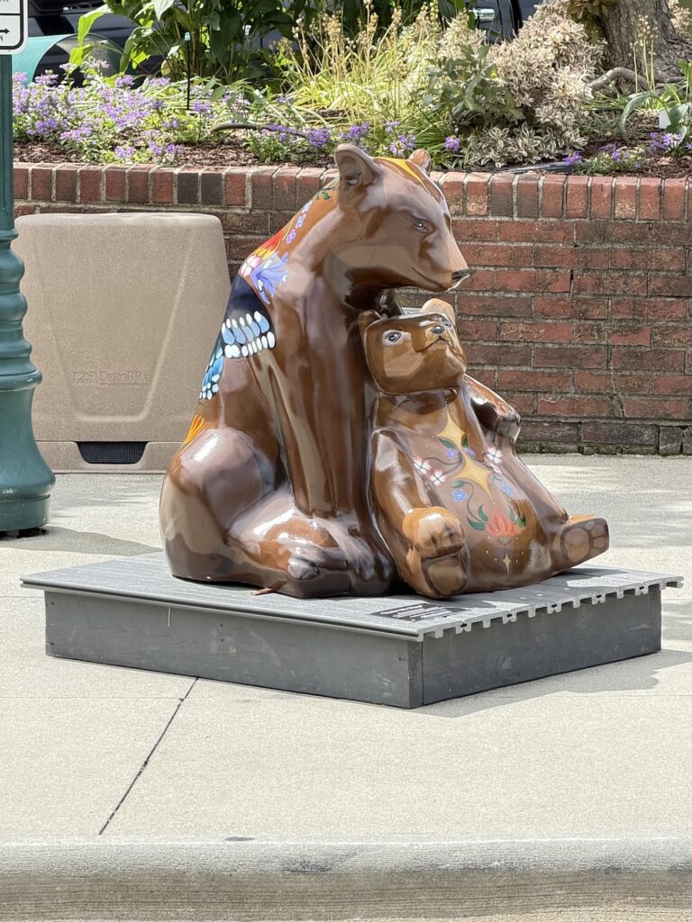 Decorative bear sculpture featuring an adult bear and cub sitting together in downtown Hendersonville, North Carolina, with colorful floral artwork painted on the statue.