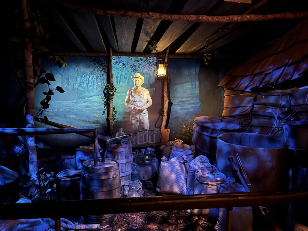Moonshine distillery exhibit with mountain man figure and rustic equipment
